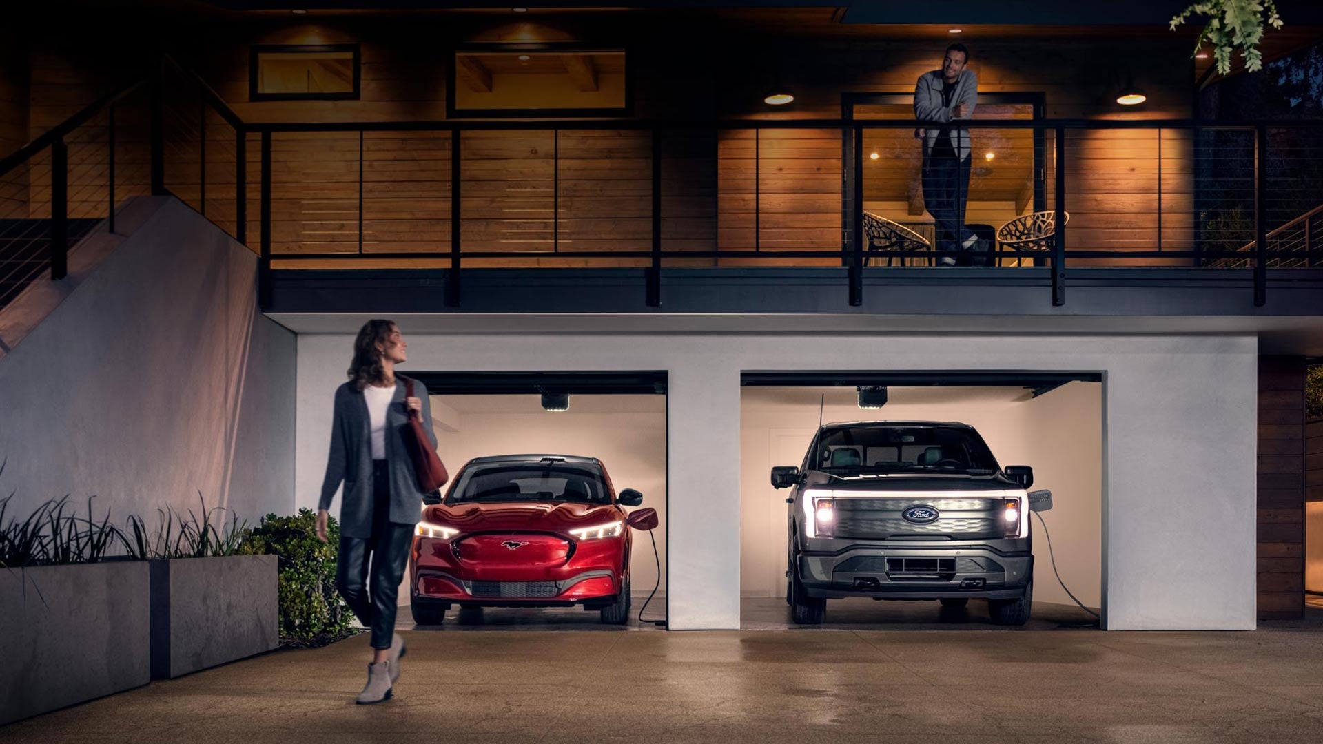 Woman walking out from home garage with a 2024 Mustang® Mach-E and Ford Lightning® truck in plugged-in and charging | Will Tiesiera Ford in Tulare CA